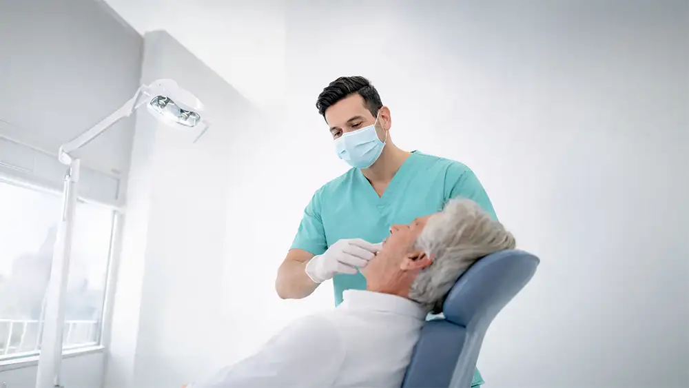 Dentista durante una visita per impianti dentali con paziente in poltrona