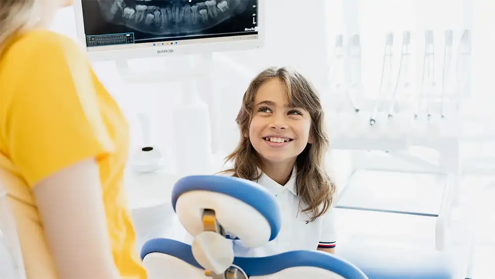 Giovane paziente sorridente in studio dentistico con monitor di diagnostica digitale